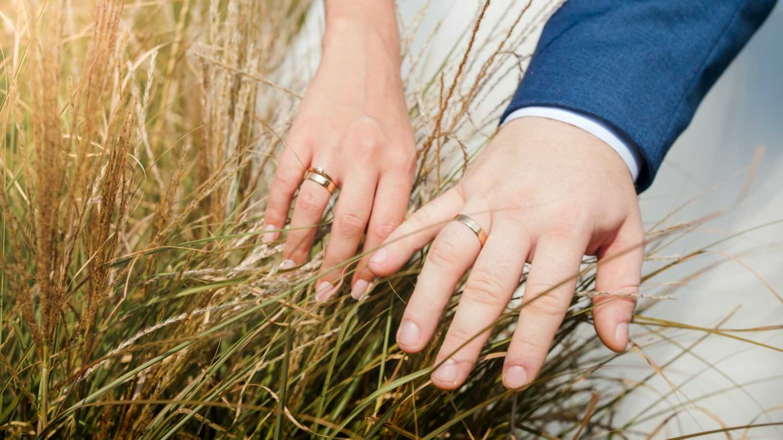 closeup-photo-of-bride-and-groom-hands-touching-grass-on-the-field-weeding-ceremony-in-nature.jpg